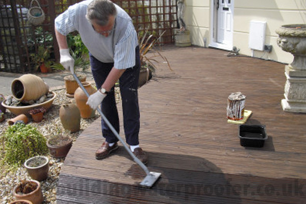 applying decking stain with applicator brush